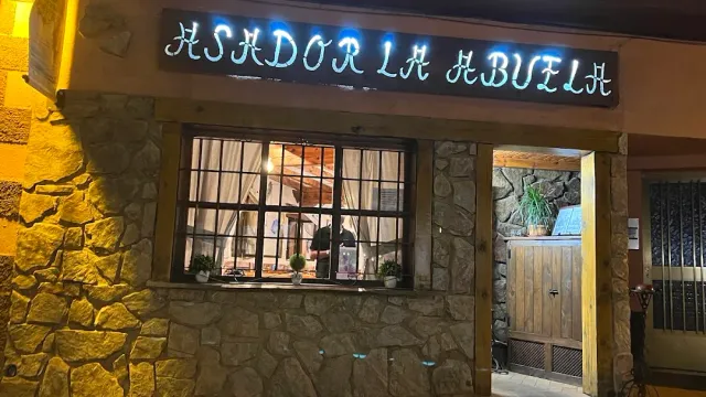 חזית אבן בלילה עם שלט ניאון מעל חלון מסורג ודלת עץ