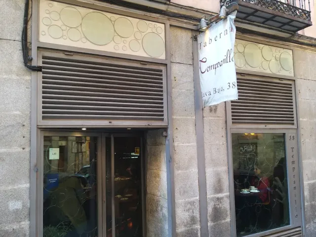 חזית אבן עם שלט תלוי, תריסים מוגפים למחצה וחלונות עם זכוכית מעוטרת