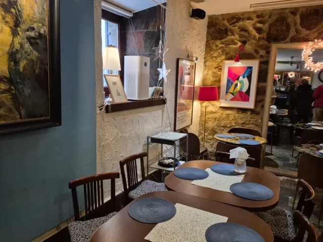 חדר אוכל עם קיר אבן, תמונות ממוסגרות ושולחנות עץ עם תחתיות כחולות